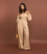 Pantalón wide leg de poliéster y elastano color beige con rayas verticales finas. Tiene corte de sastrería, doble trabilla en la cintura, bolsillos cargo laterales y cierre delantero.