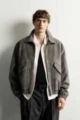 Cazadora de hombre regular fit confeccionada en tejido efecto ante, con acabado lavado, cuello solapa, manga larga, bolsillos de plastrón con solapa en la cadera, detalles elásticos en puños y cintura, y cierre frontal de cremallera.