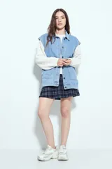 Chaleco de jean con corte oversized, diseño sin mangas, cuello camisero, cierre frontal con botones metálicos y bolsillos frontales tipo cargo.
