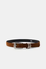Cinturón de 3 cm de ancho confeccionado en piel de ante color marrón. Presenta una hebilla metálica rectangular de estilo rústico y un detalle de triple pasador metálico.