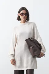 Vestido corto de punto en color beige, con cuello alto acanalado, mangas largas con puños ajustados y diseño holgado.
