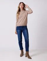 Buzo de tejido de punto color beige, con cuello alto y mangas largas. Presenta un diseño de calce ajustado con puños y ruedo acanalados.