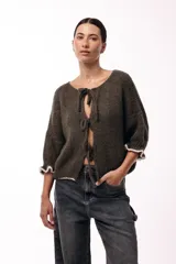 Saco de punto gris con frente abierto, cierre mediante lazos frontales y mangas con puños elásticos. Presenta una textura suave y un diseño de volumen holgado.