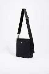 Bolso bandolera de tamaño pequeño en color verde oliva, confeccionado en poliamida con detalles en piel vacuna. Cuenta con asa larga regulable de tejido en color negro, cierre superior con cremallera y logo de la marca estampado en la parte frontal.