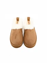 Pantuflas tipo botineta color marrón, con interior y borde superior de piel sintética blanca, suela de plataforma plana y diseño cerrado.