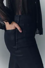 Pantalón de jean tiro medio, calce ajustado, con proceso de coating de acabado símil cuero y pierna levemente acampanada.