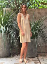 Vestido corto color beige, con escote halter y espalda descubierta.