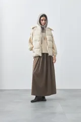 Chaleco puffer negro con diseño acolchado, capucha desmontable y cierre frontal. Cuenta con cordones ajustables en la cintura y bolsillos laterales.