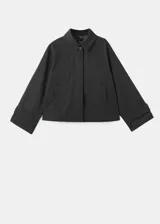 Chaqueta corta de estilo oversize en color negro, con cuello camisero, cierre frontal de botones y mangas largas con trabillas ajustables. Cuenta con dos bolsillos laterales y forro interior.