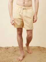 Short de baño tipo volley color amarillo claro, con cintura elástica y cordón ajustable. Presenta un diseño liso con un pequeño logo bordado en la parte inferior de la pierna izquierda.