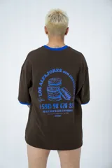Remera oversize marrón con cuello y mangas con ribete azul. Estampado en la espalda con diseño de alfajores y texto en azul.