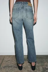 Jeans de tiro medio con corte slim leg, confeccionados en denim color beige. Presentan cintura con trabillas, diseño clásico de cinco bolsillos y cierre frontal con cremallera y botón metálico.