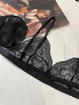 Conjunto de lencería de tres piezas en encaje negro. Incluye bralette con breteles regulables, collarín integrado con cuello ajustable y tanga regulable con corte media less.