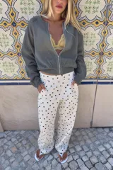 Chaqueta bomber de punto color beige con brillo sutil, cuello redondo, mangas largas abullonadas y cierre frontal de cremallera metálica.