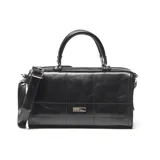 Cartera estilo baúl de cuero negro con doble asa de mano, correa ajustable y extraíble, y placa metálica con logo en el frente.
