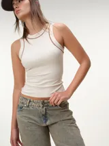 Musculosa de tela rib color marfil, con escote nadador, corte ajustado al cuerpo y costuras a contratono en color marrón.