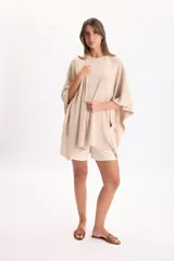 Ruana de punto color beige con hilos de lurex incorporados, diseño abierto y caída fluida.