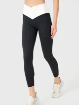 Calza deportiva de tiro alto con diseño bicolor, presentando una cintura en forma de V en color blanco y el resto de la prenda en negro. Confeccionada en tejido suave y elástico con ajuste ergonómico.