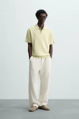 Polo de punto tejido de algodón con efecto lavado, color amarillo pálido. Presenta un calce regular fit, cuello solapa con cierre frontal de tres botones y manga corta.