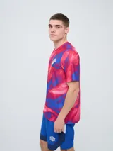 Remera de entrenamiento Umbro del Club Nacional de Football, modelo Press, para hombre. Diseño en tonos de rojo con patrón estampado tipo humo o abstracto, cuello redondo y mangas cortas. Incluye el logo de Umbro y el escudo del club en el pecho.