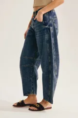 Jean barrel de tiro alto en denim azul con lavado desgastado, silueta curva y costuras decorativas a la altura de la rodilla.