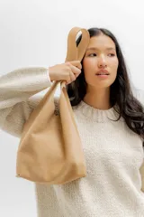 Bolso tote pequeño de cuero color beige, con doble asa corta y diseño minimalista.