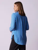 Camisa celeste con rayas verticales blancas, de corte clásico, cuello a la base, escote en V y abertura central con botones.