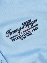 Chomba celeste de piqué de algodón elástico, corte slim, con cuello clásico, cartera de cuatro botones y logo de Tommy Hilfiger bordado en el pecho y en la manga.