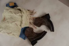 Bota estilo western de caña media, confeccionada en una combinación de cuero texturizado en la parte inferior y gamuza en la caña. Presenta costuras decorativas en contraste y suela de goma robusta con plataforma.