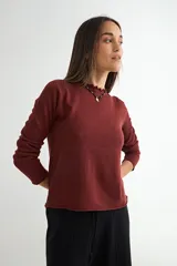 Sweater de punto negro con cuello redondo y detalle de borde ondulado, de manga larga y corte clásico.