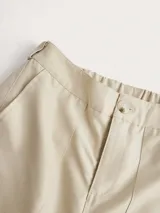 Pantalón cargo color crema de corte baggy, con múltiples bolsillos en los laterales y aberturas en los tobillos.
