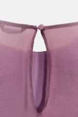 Blusa de cuello redondo y manga larga, color marrón oscuro. Presenta volantes en el frente y en los puños, y un bajo asimétrico. Cierre en la espalda con abertura y botón forrado.