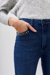 Jean de tiro medio y corte slim, confeccionado en denim azul con lavado localizado y apliques de hotfix en los bolsillos delanteros.