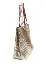 Bolso tipo tote de diseño acolchado con costuras en forma de V, acabado metalizado dorado. Cuenta con correas de hombro de cinta con el logo de la marca estampado.