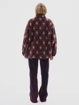 Campera de sherpa con estampado geométrico en tonos bordó y rosa, cuello alto, cierre frontal con broches a presión y bolsillos frontales con ribetes en contraste.