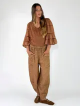 Pantalón bombacho de lino color marrón, de corte holgado, con cintura elástica, bolsillos frontales aplicados y tobillos ajustados.