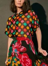 Vestido largo con estampado de lunares multicolores y flores grandes. Tiene cuello camisero, mangas cortas y corte a la cintura con falda amplia.