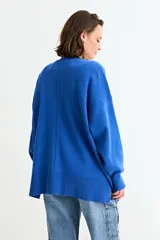 Cardigan de punto color fucsia, con cuello en V, cierre frontal con botones y bolsillos laterales. Presenta un diseño holgado con mangas largas y puños acanalados.