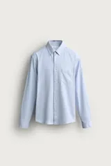 Camisa de corte regular fit confeccionada en tejido de algodón y lino, en color celeste. Presenta cuello abotonado, manga larga con puño abotonado, un bolsillo de parche en el pecho y cierre frontal con botones.
