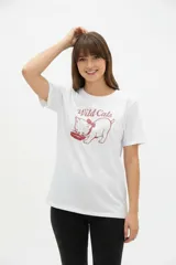 Remera de algodón blanca, de corte holgado, con cuello redondo y diseño estampado en el centro que incluye un gato comiendo de un plato y la inscripción 'Wild Cats'.