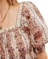 Blusa de algodón con silueta babydoll, escote cuadrado y mangas cortas abullonadas. Presenta un diseño estampado con rayas verticales y motivos florales.