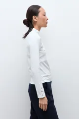 Media polera de manga larga con cuello alto y detalle de frunces en los puños, confeccionada en tejido suave y elástico.