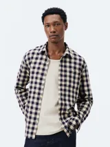 Camisa de manga larga con estampado a cuadros grandes en azul y blanco. Tiene cuello clásico, cierre con botones y un bolsillo en el pecho.