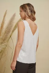 Musculosa de lentejuelas doradas con doble escote en V, tanto en el frente como en la espalda. Presenta breteles anchos y un corte levemente acampanado.