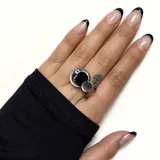 Anillo plateado con diseño de luna y círculo negro.