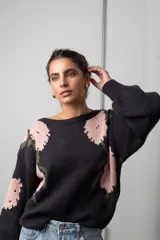 Buzo de punto color negro con estampado floral en tonos rosado y verde, de corte oversize, cuello redondo y mangas globo.