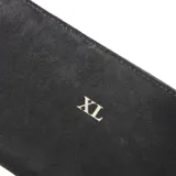 Billetera rectangular de símil gamuza color negro, con cierre perimetral y logo "XL" metálico dorado en el frente. Incluye compartimentos internos para tarjetas y una división central con cierre.