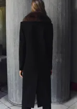 Abrigo largo de corte recto confeccionado en mezcla de lana, con cuello de solapa y cuello de pelo sintético extraíble. Presenta cierre frontal con botones, mangas largas y dos bolsillos con solapa en la parte delantera.