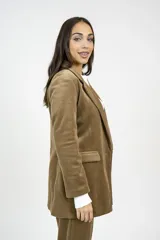 Blazer de pana color marrón con solapas clásicas, cierre frontal con botones y bolsillos con solapa. Presenta un corte entallado y estructura formal.