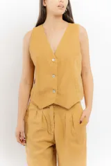 Chaleco de lino color bordó con escote en V y cierre frontal de botones. Presenta costuras a contratono y un diseño liviano ideal para el verano.